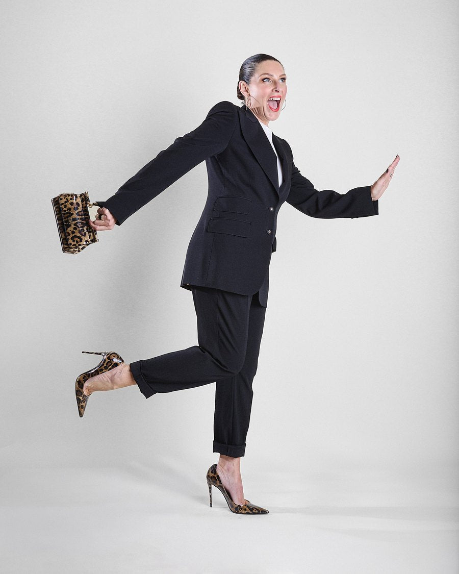 Jacqui Hutton mid-stride in a black suit, laughing, full of energy