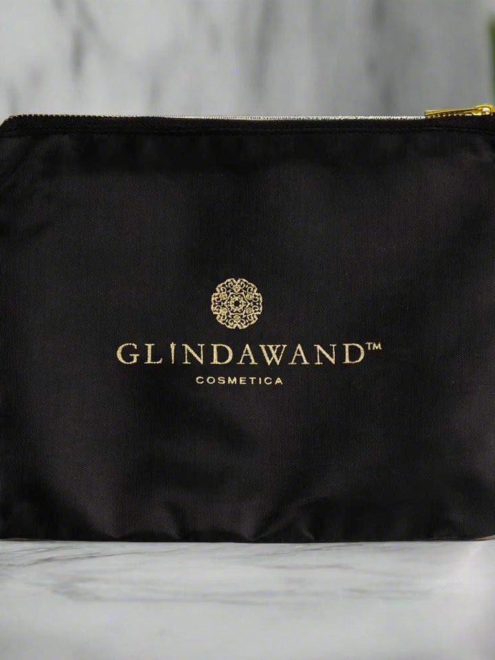 The black GlindaWand Cosmetica canvas clutch with gold zip on a marble bench