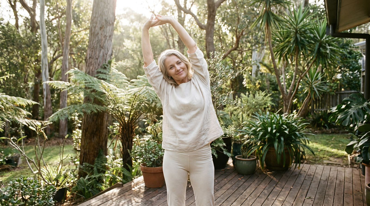 A woman in her fifties stretching in a leafy garden at sunrise