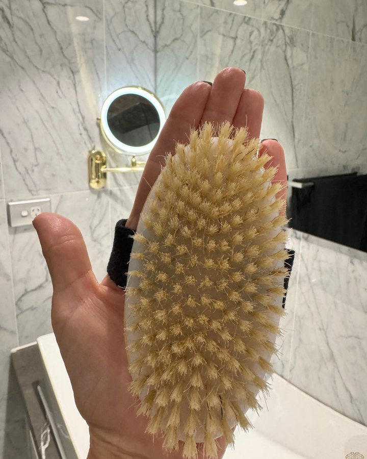 The FoYL Body Brush held in the palm, natural bristles facing up